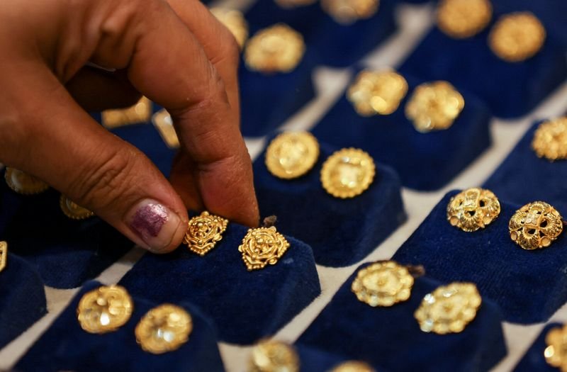 © Reuters. A woman picks a gold earring at a jewellery shop in the old quarters of Delhi, India, May 24, 2023. REUTERS/Anushree Fadnavis/File Photo