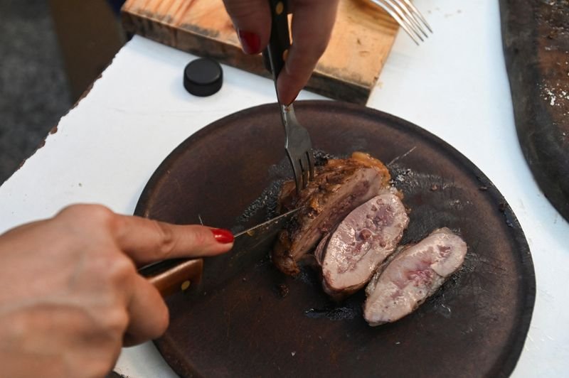 © Reuters. FILE PHOTO: A woman slices beef at a barbecue at her home in Buenos Aires, Argentina June 23, 2024. REUTERS/Martin Cossarini/File Photo